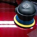 Close-up of a high-speed polisher refining a car's paintwork.